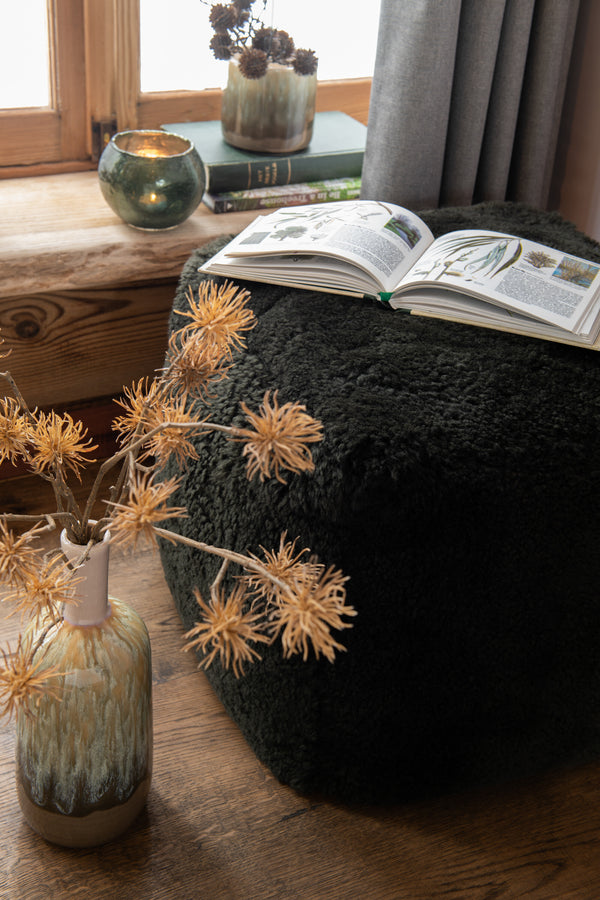 Stylish square stool with sheepskin in green Design meets comfort