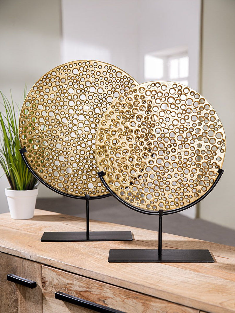 Hive - Gold-colored, perforated object on a black metal stand by GILDE
