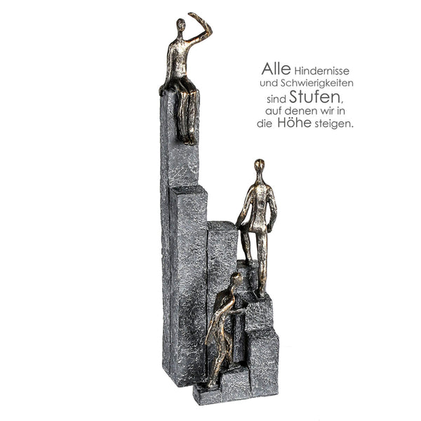 Skulptur OUT UP Climbing  3 Figuren bronzefarbend auf Stufen, Basis in Steinoptik grau mit Spruchanhänger